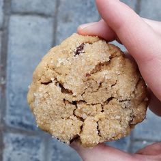 a close up of a person holding a cookie in their hand on a brick surface