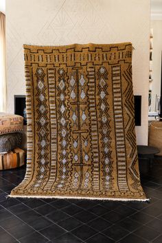 a brown and white blanket sitting on top of a black tile floor next to a fireplace