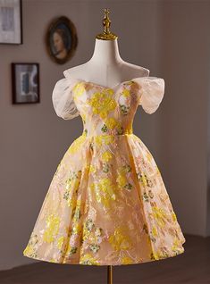 Alight with charm! This homecoming dress in soft pastel yellow offers a dreamy aesthetic, adorned with vibrant yellow and pink floral embroidery that seems to burst into bloom across the fabric. The delicate tulle overlay and floaty, puffed sleeves provide a soft silhouette, while the fitted bodice and flared skirt celebrate the classic beauty of vintage fashion. The neckline subtly scoops to frame the face, and the dress ties beautifully at the waist with a sash, enhancing its fairy-tale quality. This dress is not just an outfit but a statement of elegance and youthful exuberance, perfect for making a grand entrance at your next formal event. Off The Shoulder Homecoming Dress, Prom Dress Off The Shoulder, Brown Prom Dresses, Champagne Homecoming Dresses, Yellow Homecoming Dresses, Knee Length Prom Dress, Orange Prom Dresses, Purple Homecoming Dress, Burgundy Homecoming Dresses