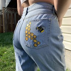 the back of a woman's jeans with bees on it and honeycombs painted on them