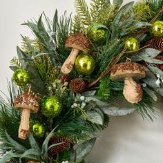 a wreath with green ornaments and pine cones