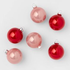 five red christmas ornaments on a white surface