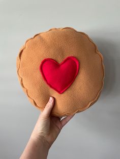 a hand holding a heart shaped cookie with a red felt on the top and bottom