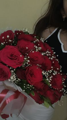 a woman holding a bouquet of red roses