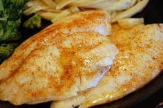 some food is sitting on a plate with fries and broccoli in the background