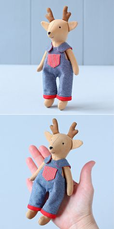 a hand holding a small stuffed animal that is wearing overalls and a red striped shirt