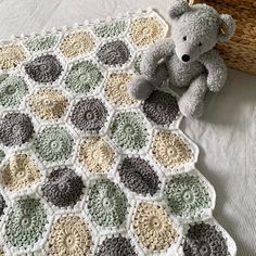 a teddy bear sitting on top of a crocheted blanket