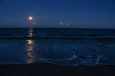 the moon is shining over the ocean at night