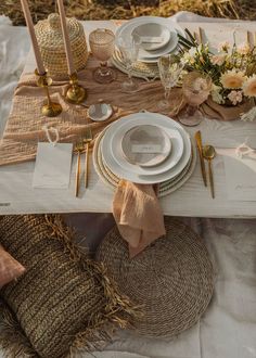 the table is set with white plates and silverware, gold place settings and burlap napkins