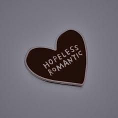 a heart shaped chocolate sticker with the words hopeless romantic written in white on it