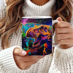 a woman holding a coffee mug with a painting of a t - rex on it