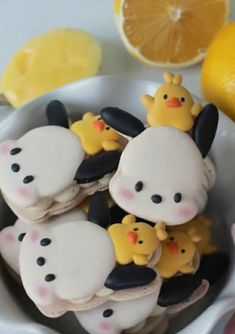 there are some cookies decorated like animals in a bowl next to lemons and other food items