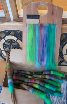 several different colored yarns are in a box on the floor next to a pair of knitting needles