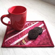 a red mug and two cookies on a place mat