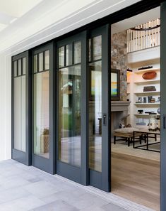 an open glass door leading into a room with tables and chairs on the outside wall