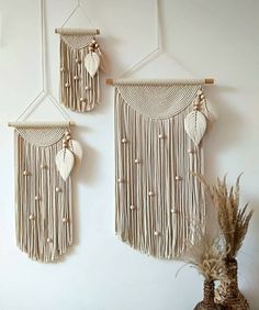 three wall hangings made out of macrame with leaves and shells on them