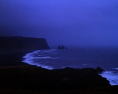 a group of people standing on top of a cliff next to the ocean