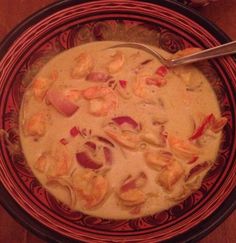 a bowl filled with soup and shrimp on top of a wooden table