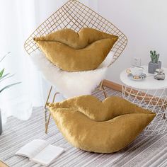 two chairs and a table in a room with plants on the floor, one chair has a cushion that is shaped like a mouth