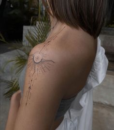 the back of a woman's shoulder with a sun and stars tattoo on it