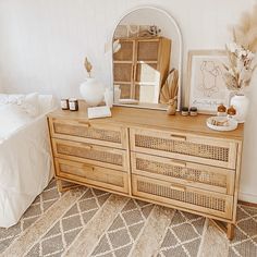 a wooden dresser sitting next to a bed with white sheets and pillows on top of it