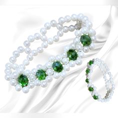 two bracelets with white pearls and green crystal beads on a white satin fabric background