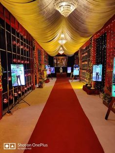 a long red carpeted hallway with white drapes on the ceiling and televisions