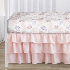 a white crib with a pink bed skirt