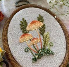 a close up of a embroidery on a wooden hoop with flowers and leaves in it