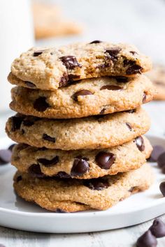 a stack of chocolate chip cookies sitting on top of a white plate next to a glass of milk