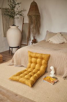 a bed room with a neatly made bed and pillows on the floor next to it