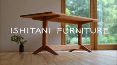 a wooden table sitting on top of a hard wood floor next to a vase filled with flowers