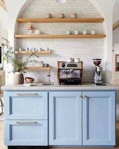 a kitchen with blue cabinets and shelves filled with pots, pans and coffee machines