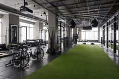 an indoor gym with green carpeting and exercise equipment on the walls, along with large windows