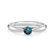 a white gold ring with a blue topazte stone in the center, on a white background