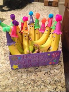 a bunch of bananas that are sitting in a box on a counter top with happy birthday written on them