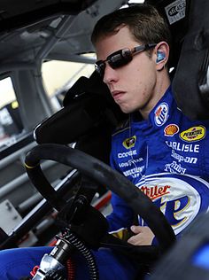 a man sitting in the driver's seat of a race car with his headphones on