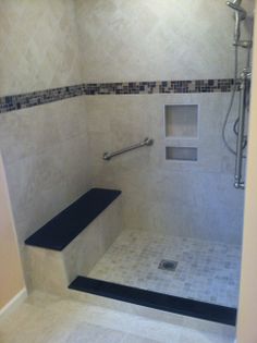 a walk in shower sitting next to a tiled floor and white walls with black accents