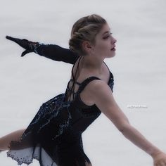 a female figure skating on the ice in a black leotard and blue dress