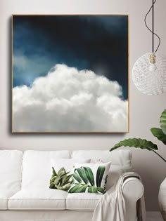 a living room with a white couch and large painting on the wall above it that has clouds in the sky