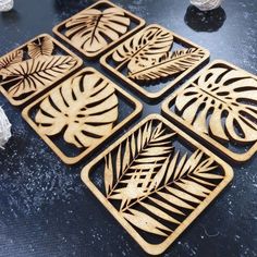 four wooden coasters with leaf designs on them sitting on a table next to rocks