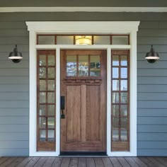 the front door of a house with two lights on each side and an entryway