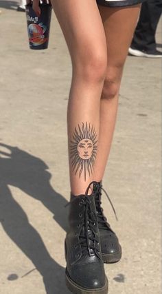 a woman's legs with sun tattoo on them and black lace - up boots