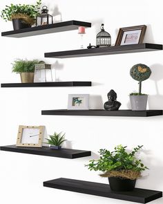 three black floating shelves with plants and pictures on them, one has a potted plant