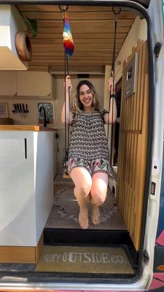 a woman sitting in the back of a van with her feet up on a swing