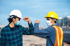 two construction workers wearing masks and safety vests