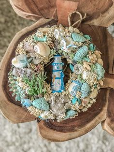 a wreath made out of seashells and other sea creatures is hanging on a piece of wood