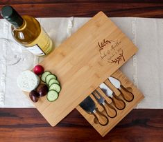 a cutting board with knifes, cucumbers and cheese on it next to a bottle of wine