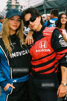 two women standing next to each other wearing racing gear