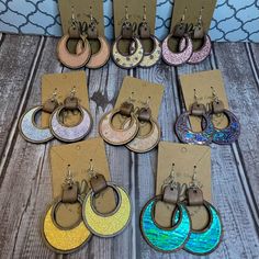 six pairs of earrings are on display in front of a wooden table with other items